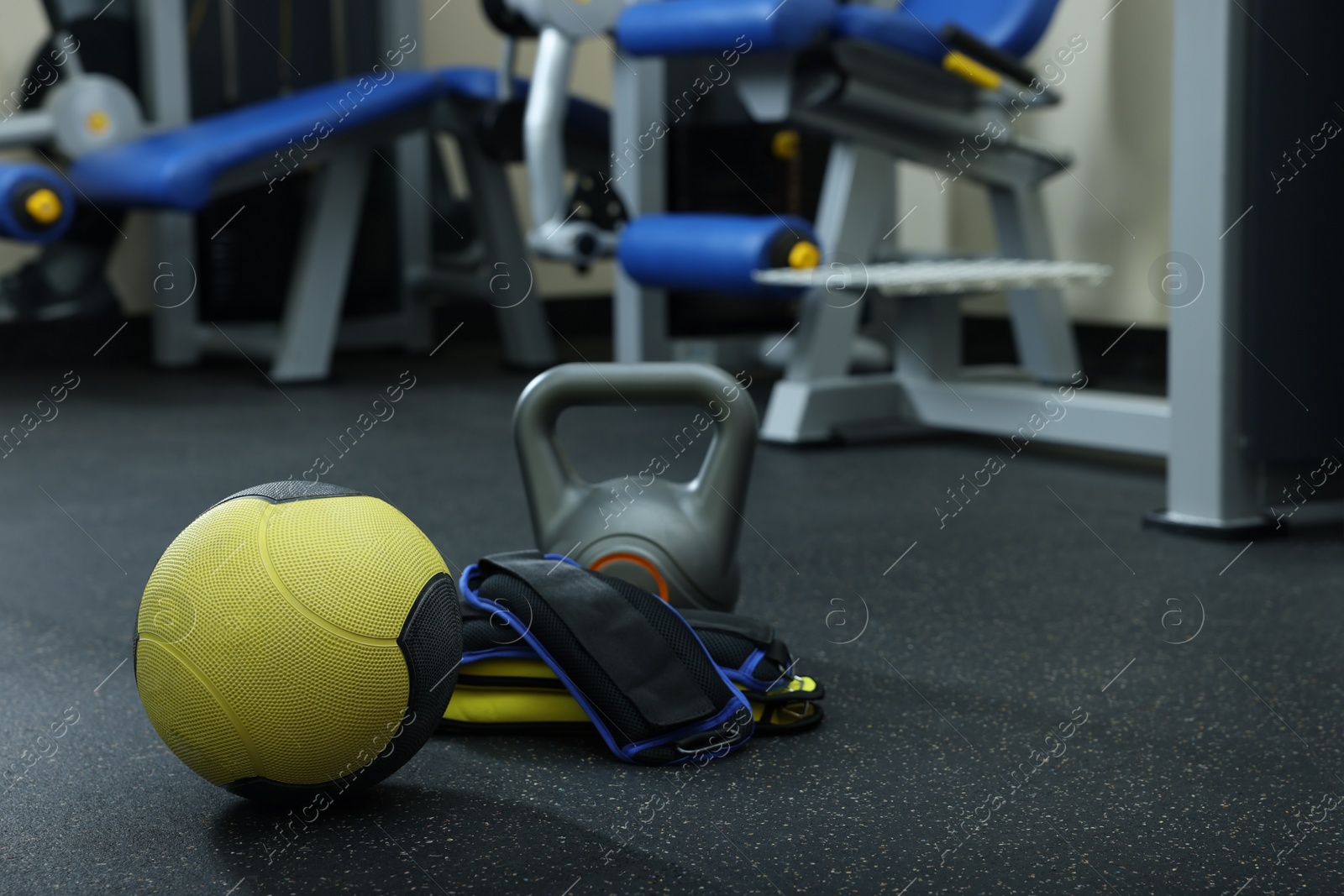 Photo of Yellow medicine ball, kettlebell and weighting agents on floor in gym, space for text