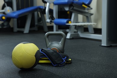 Photo of Yellow medicine ball, kettlebell and weighting agents on floor in gym, space for text