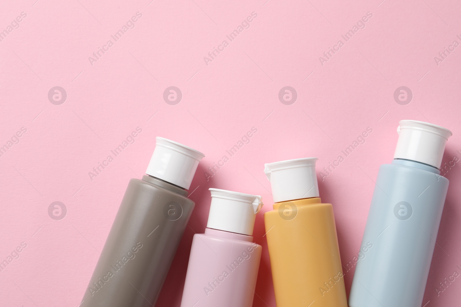 Photo of Cosmetic travel kit on pink background, flat lay. Space for text