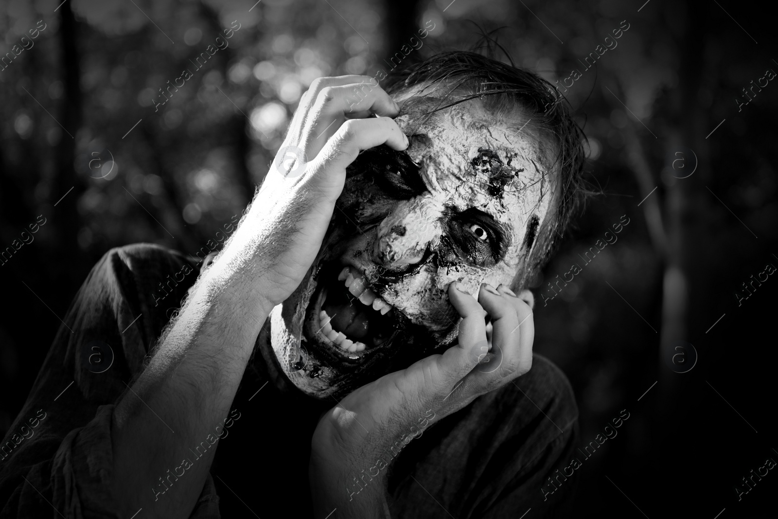 Photo of Scary zombie outdoors, black and white effect. Halloween monster