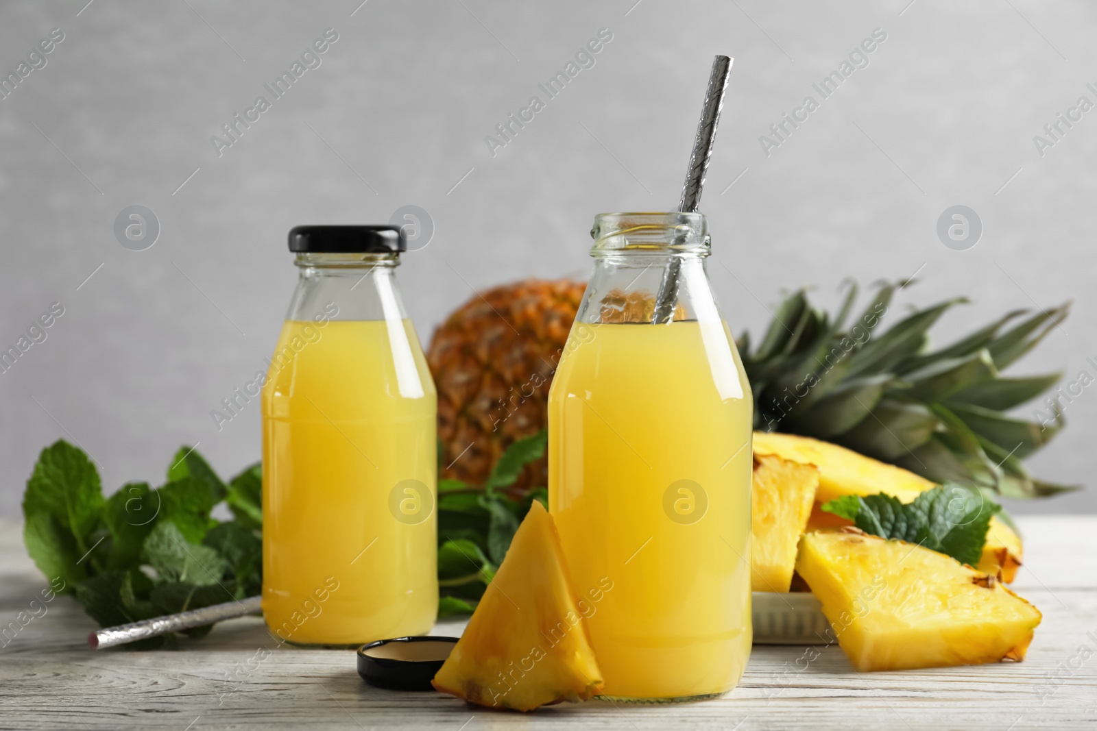 Photo of Delicious pineapple juice and fresh fruit on white table