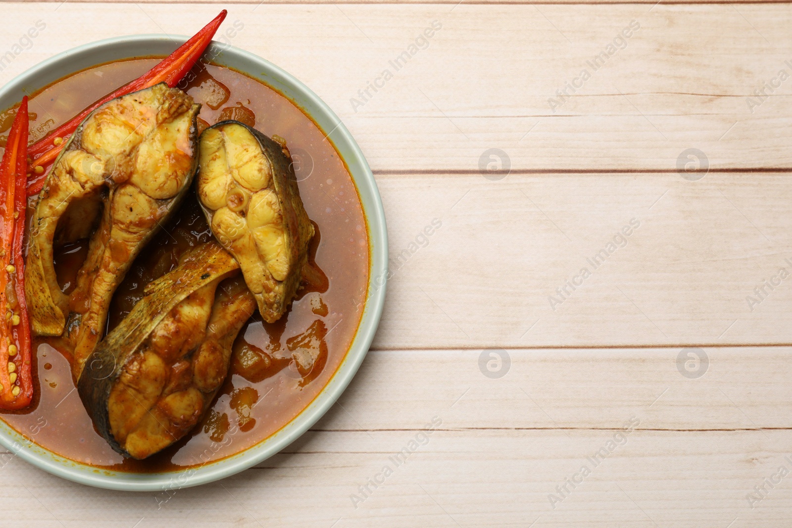 Photo of Tasty fish curry on white wooden table, top view. Space for text. Indian cuisine