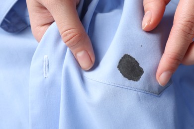 Woman holding shirt with black ink stain, top view