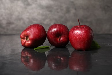 Photo of Wet red apples on dark grey table