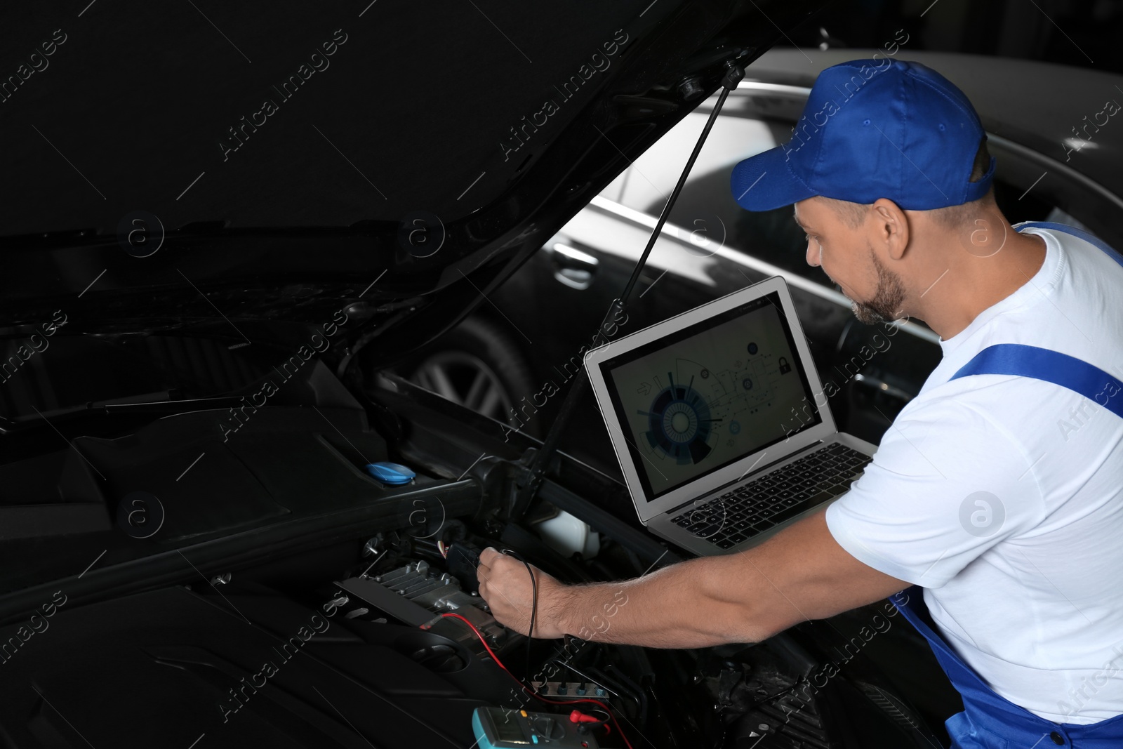 Photo of Mechanic with laptop doing car diagnostic at automobile repair shop