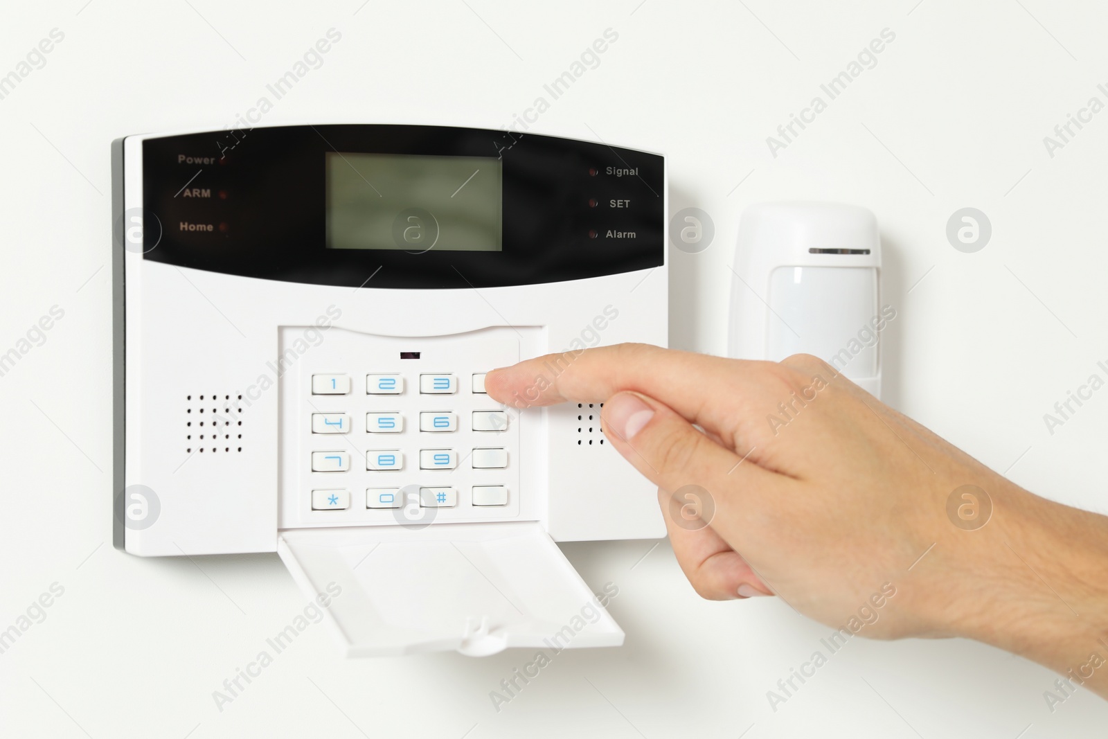 Photo of Man entering code on home security system indoors, closeup