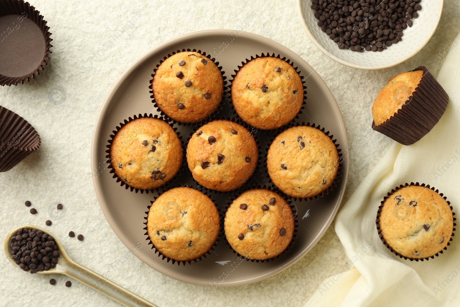 Photo of Delicious sweet muffins with chocolate chips on light textured table, flat lay