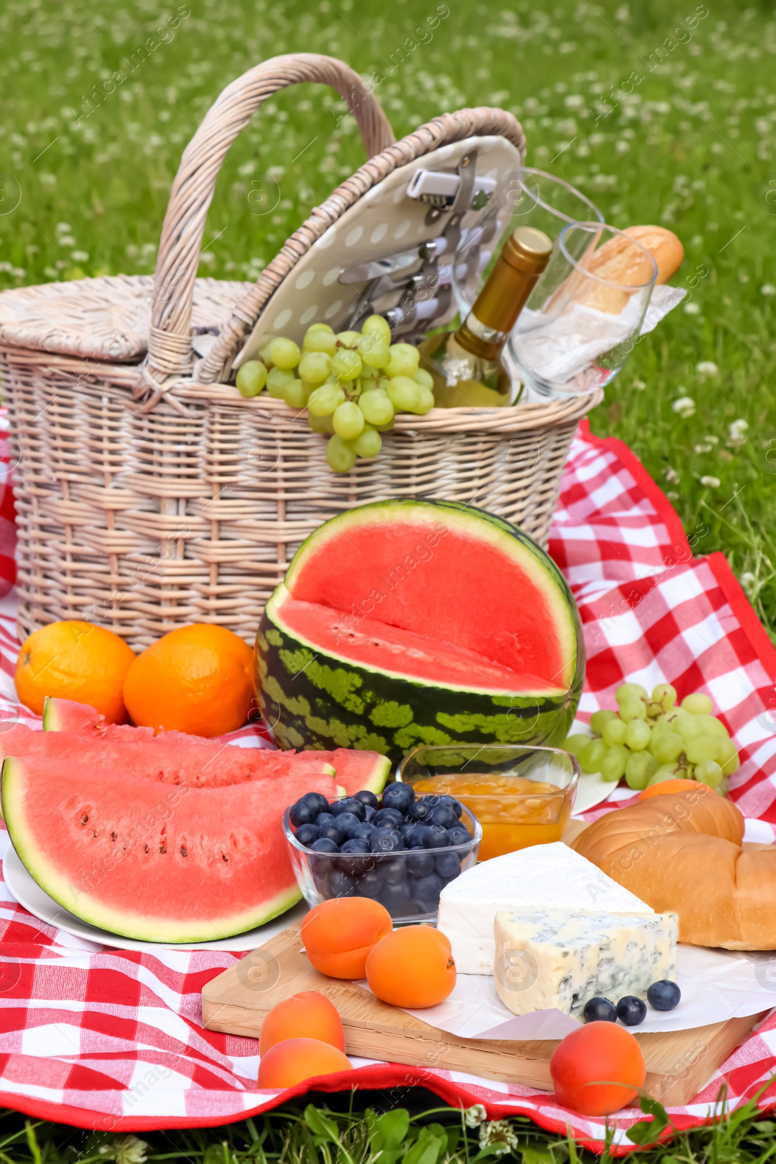 Photo of Picnic blanket with delicious food and wine outdoors on summer day