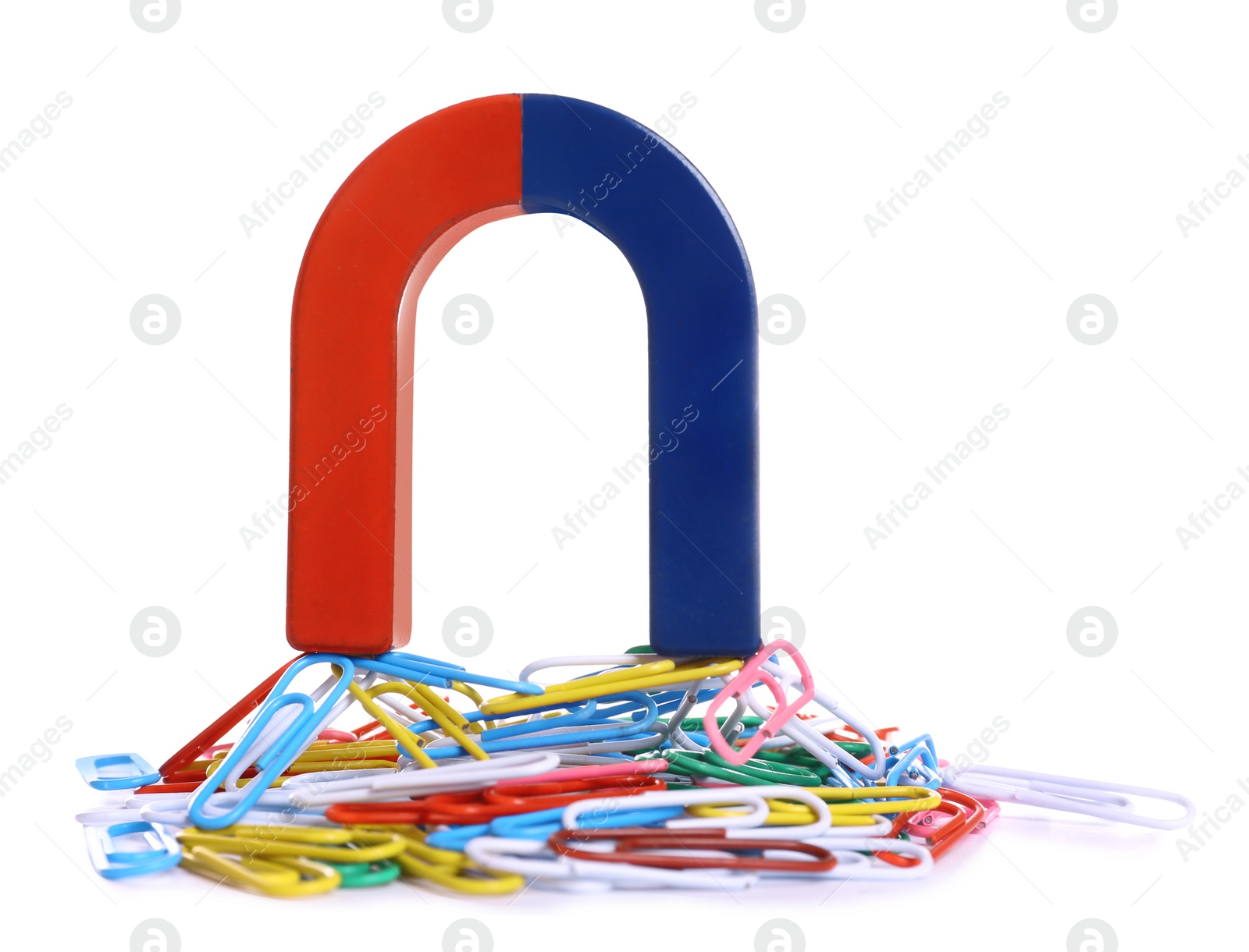 Photo of Horseshoe magnet attracting paper clips on white background