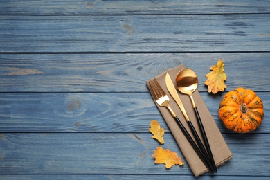 Cutlery, autumn leaves and pumpkin on blue wooden table, flat lay with space for text. Thanksgiving Day