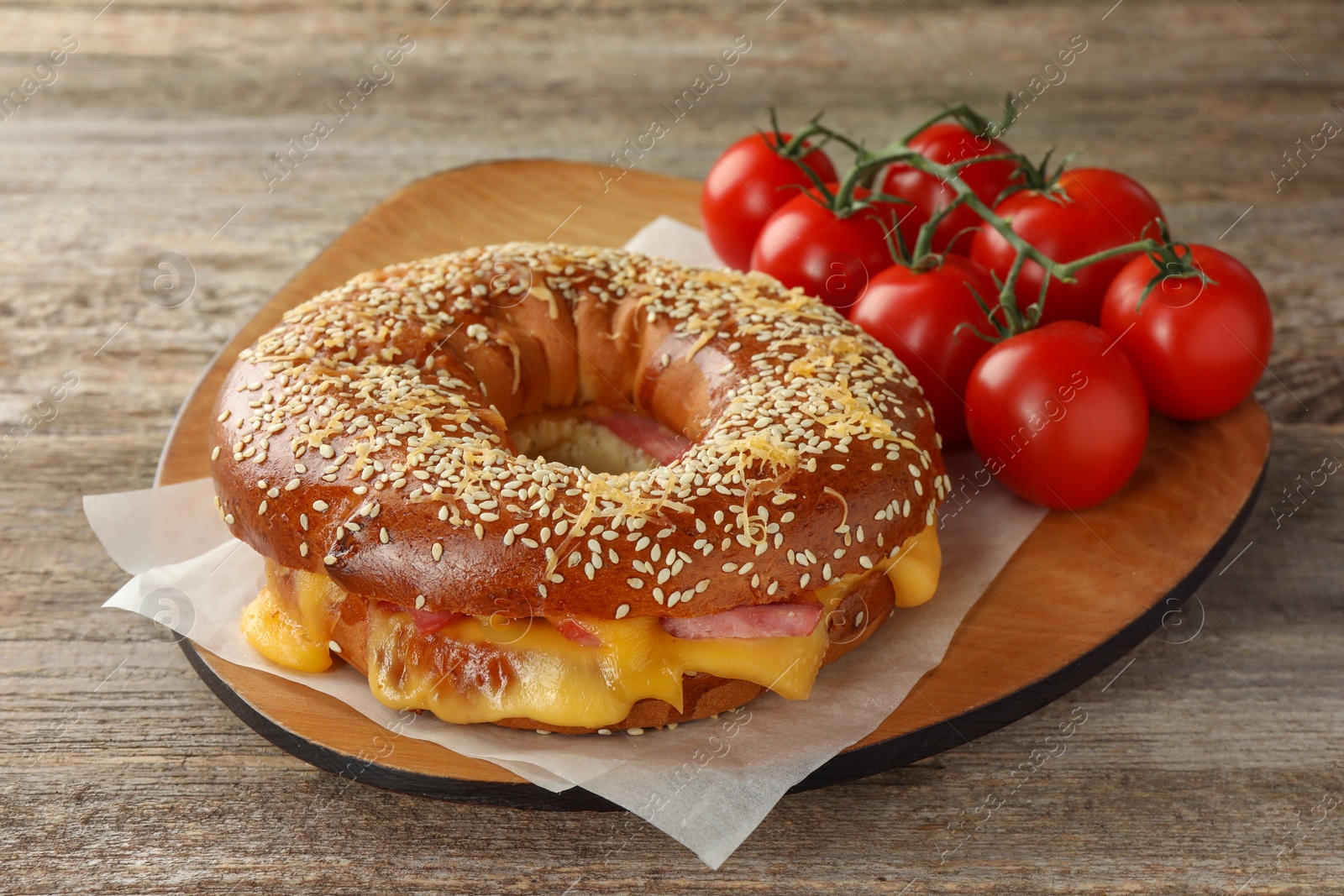 Delicious bagel with ham, cheese and tomatoes on wooden table Photo of Delicious bagel with ham, cheese and tomatoes on wooden table