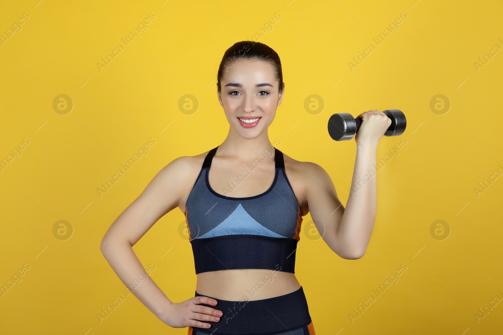 Photo of Woman with dumbbell as girl power symbol on yellow background. 8 March concept