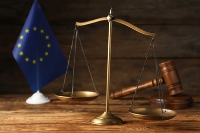 Photo of Scales of justice, judge's gavel and European Union flag on wooden table