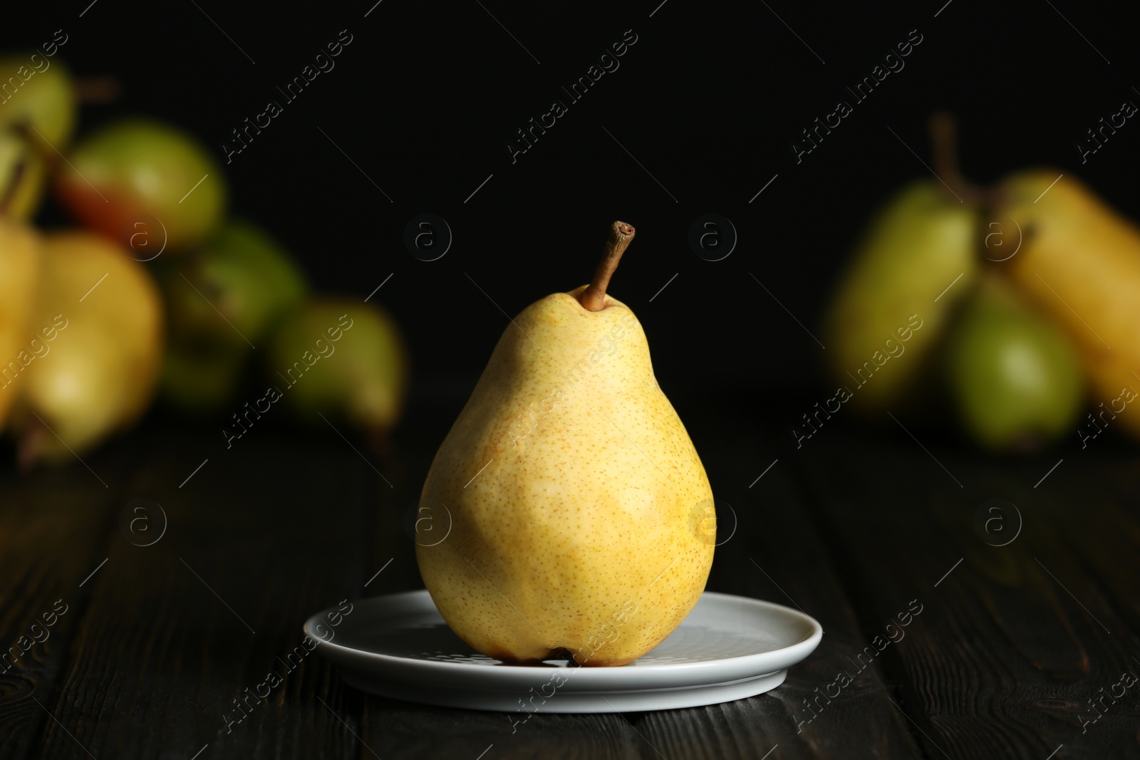 Photo of Plate with fresh ripe pear on table against blurred background