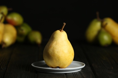 Photo of Plate with fresh ripe pear on table against blurred background