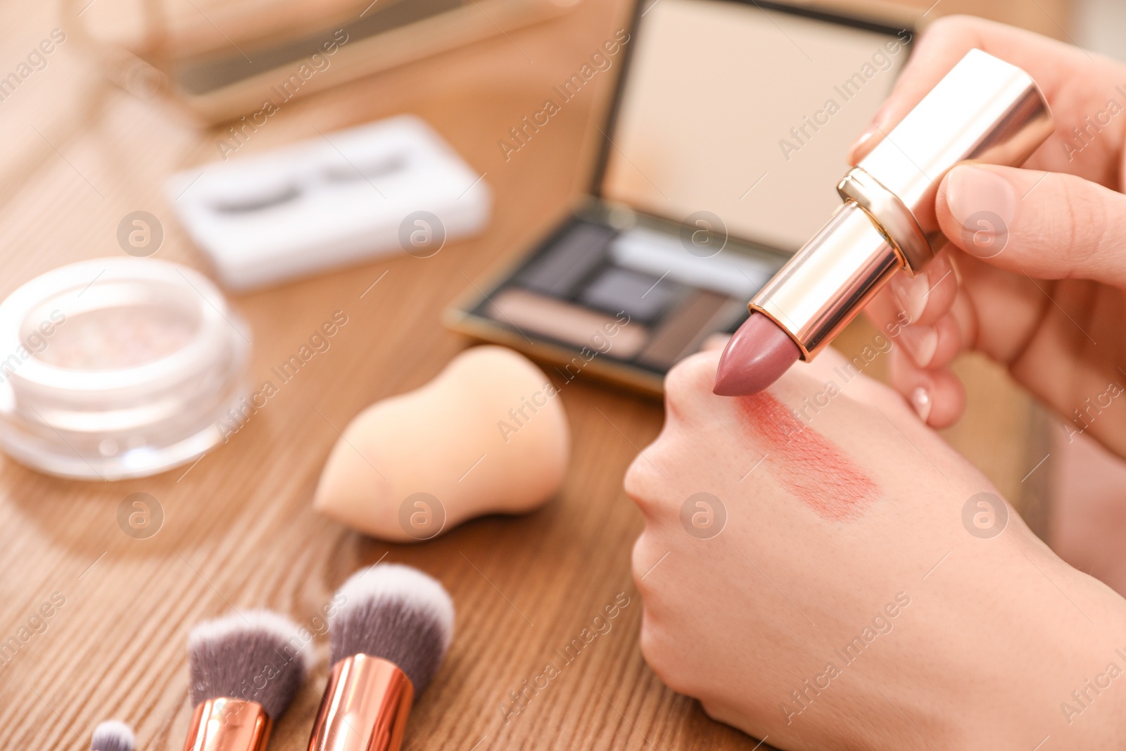 Photo of Beauty blogger doing lipstick swatch at table, closeup