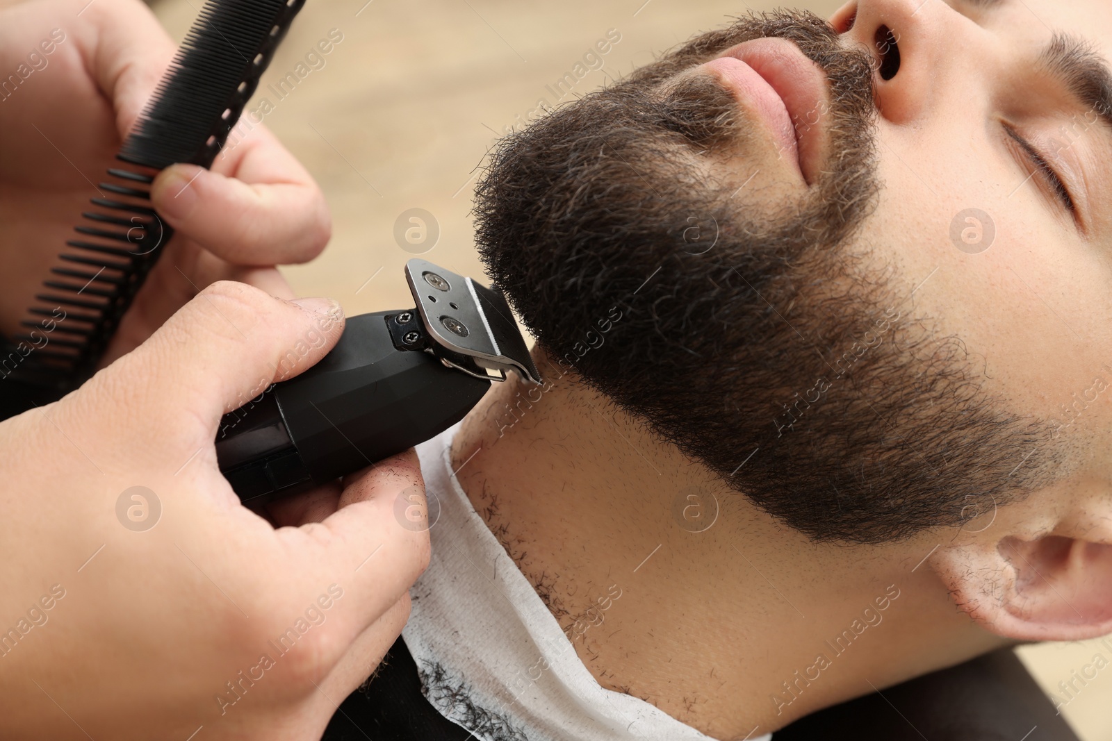 Photo of Professional hairdresser working with client in barbershop, closeup