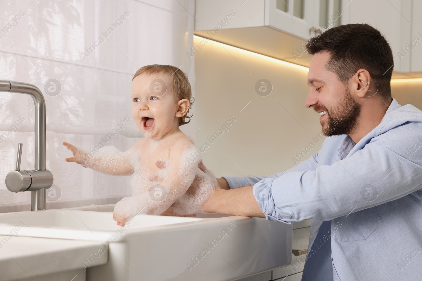 Photo of Father washing his little baby in sink at home