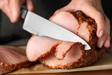 Woman cutting ham at table, closeup. Festive dinner