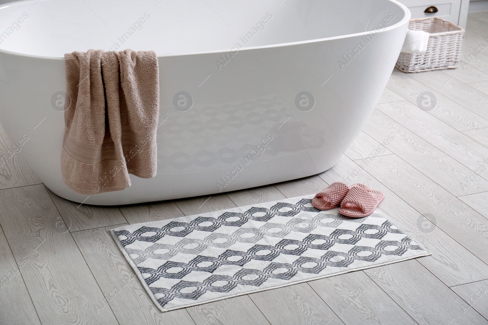 Photo of Stylish mat and slippers on floor near tub in bathroom. Interior design