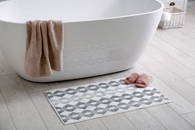 Photo of Stylish mat and slippers on floor near tub in bathroom. Interior design