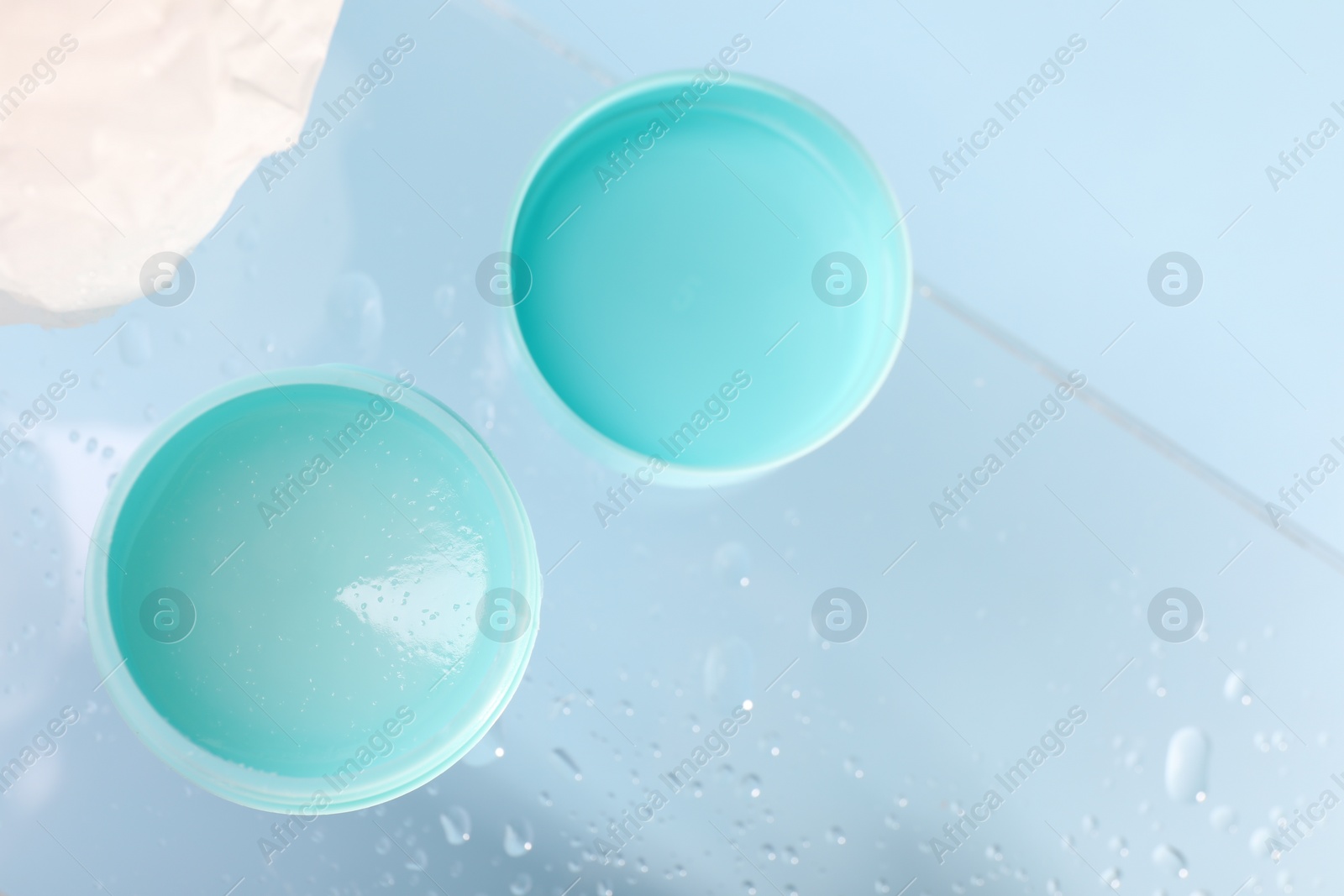 Photo of Lip balm and water drops on glass surface, flat lay