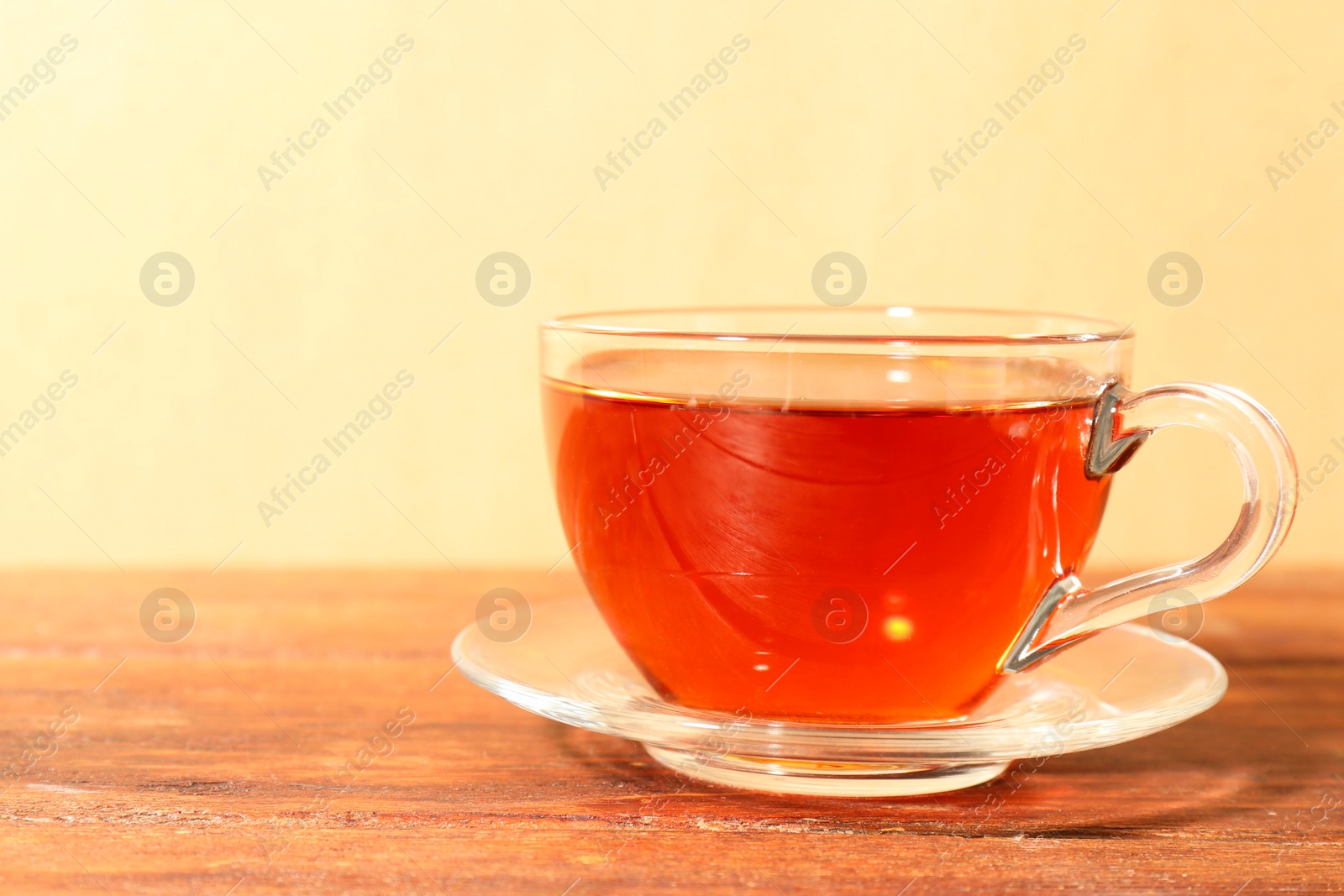 Photo of Glass cup of tea on wooden table. Space for text