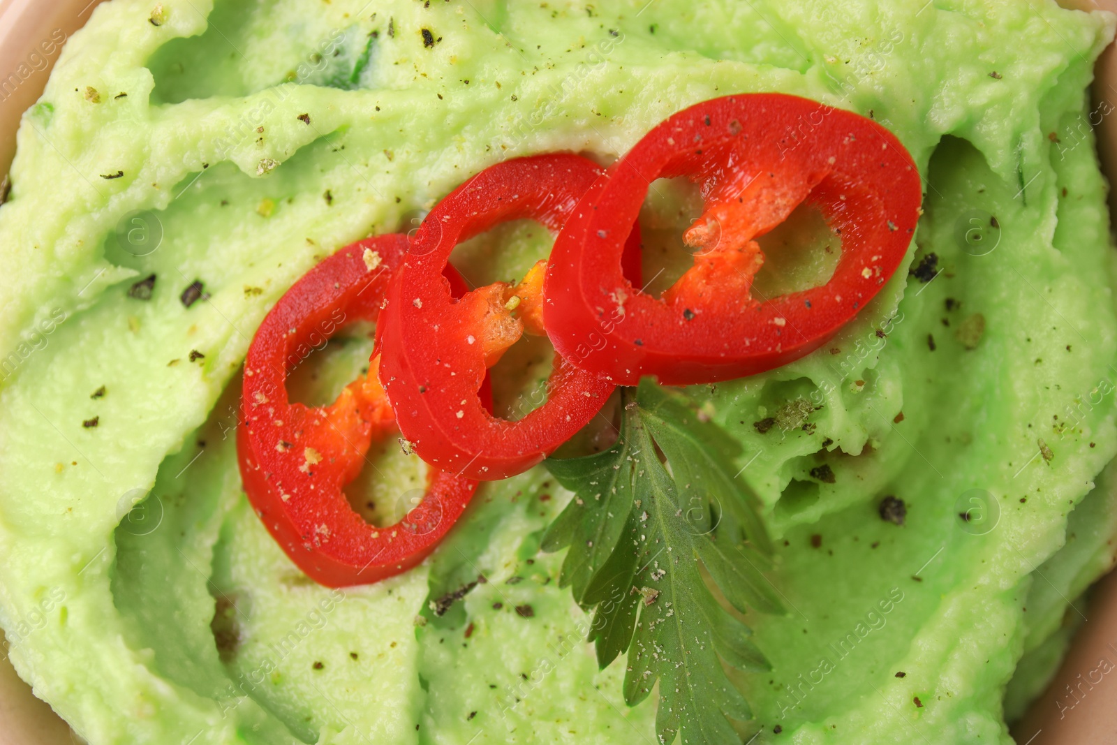 Photo of Delicious guacamole with chili pepper and parsley as background, top view