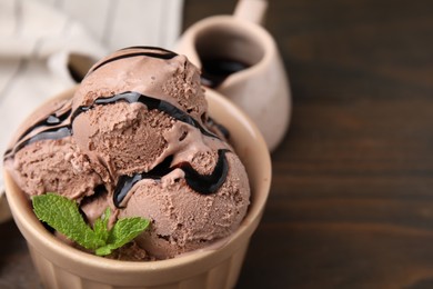 Photo of Bowl of tasty chocolate ice cream on table, closeup. Space for text