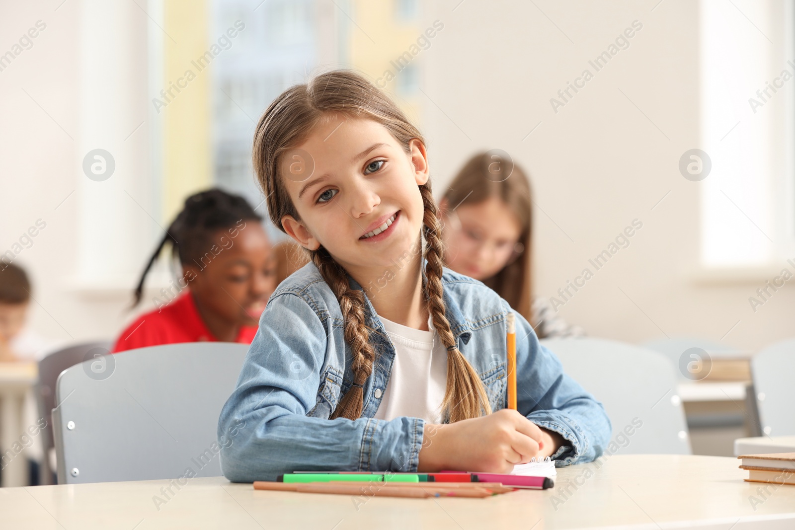 Photo of Portrait of smiling little girl studying in classroom at school