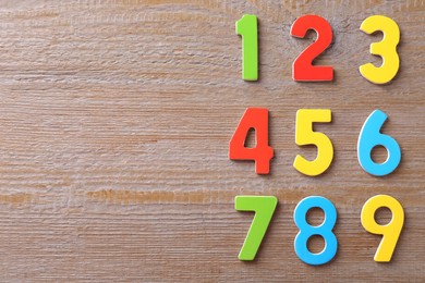 Colorful numbers on wooden table, flat lay. Space for text