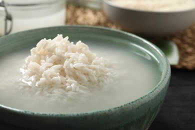 Bowl with rice soaked in water on table, closeup