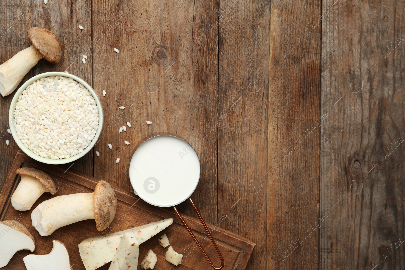 Photo of Flat lay composition with different ingredients on wooden table, space for text. Risotto recipe