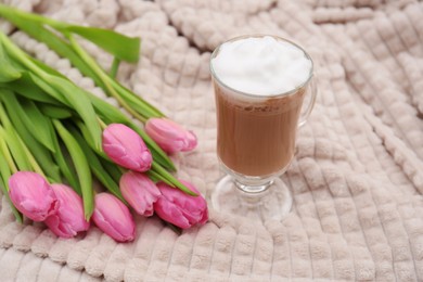 Photo of Glass of delicious cocoa and pink tulips on light blanket