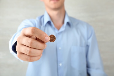 Man holding coin on grey background, closeup view