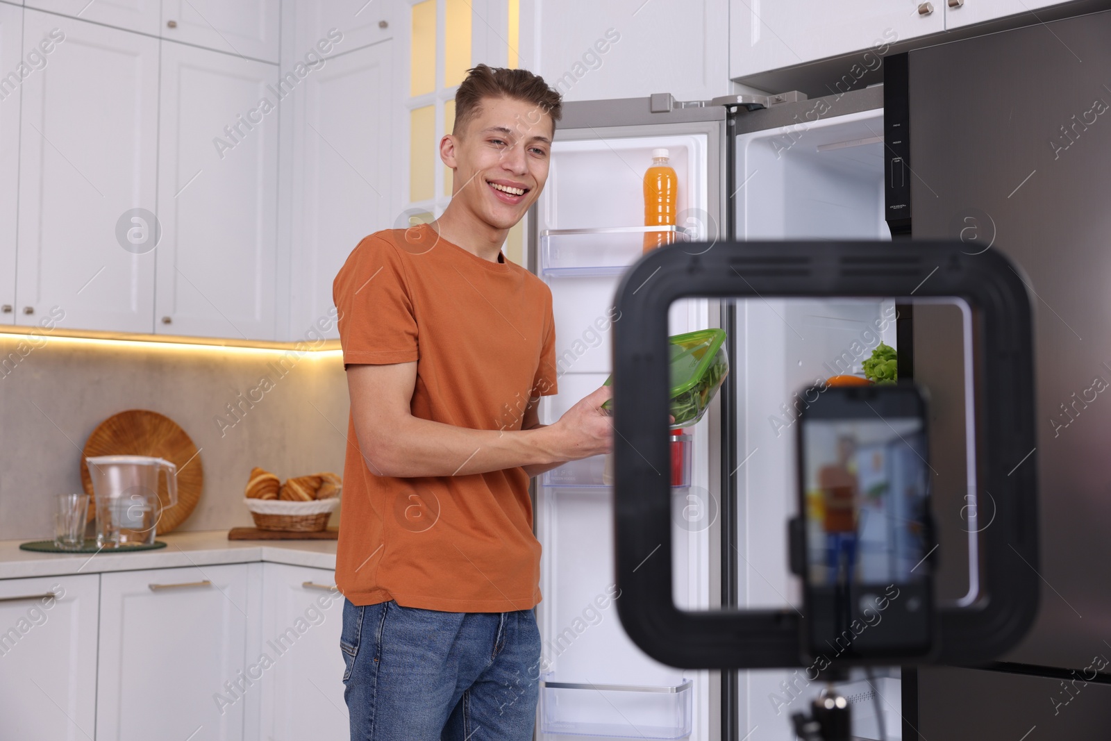 Photo of Smiling food blogger explaining something while recording video in kitchen