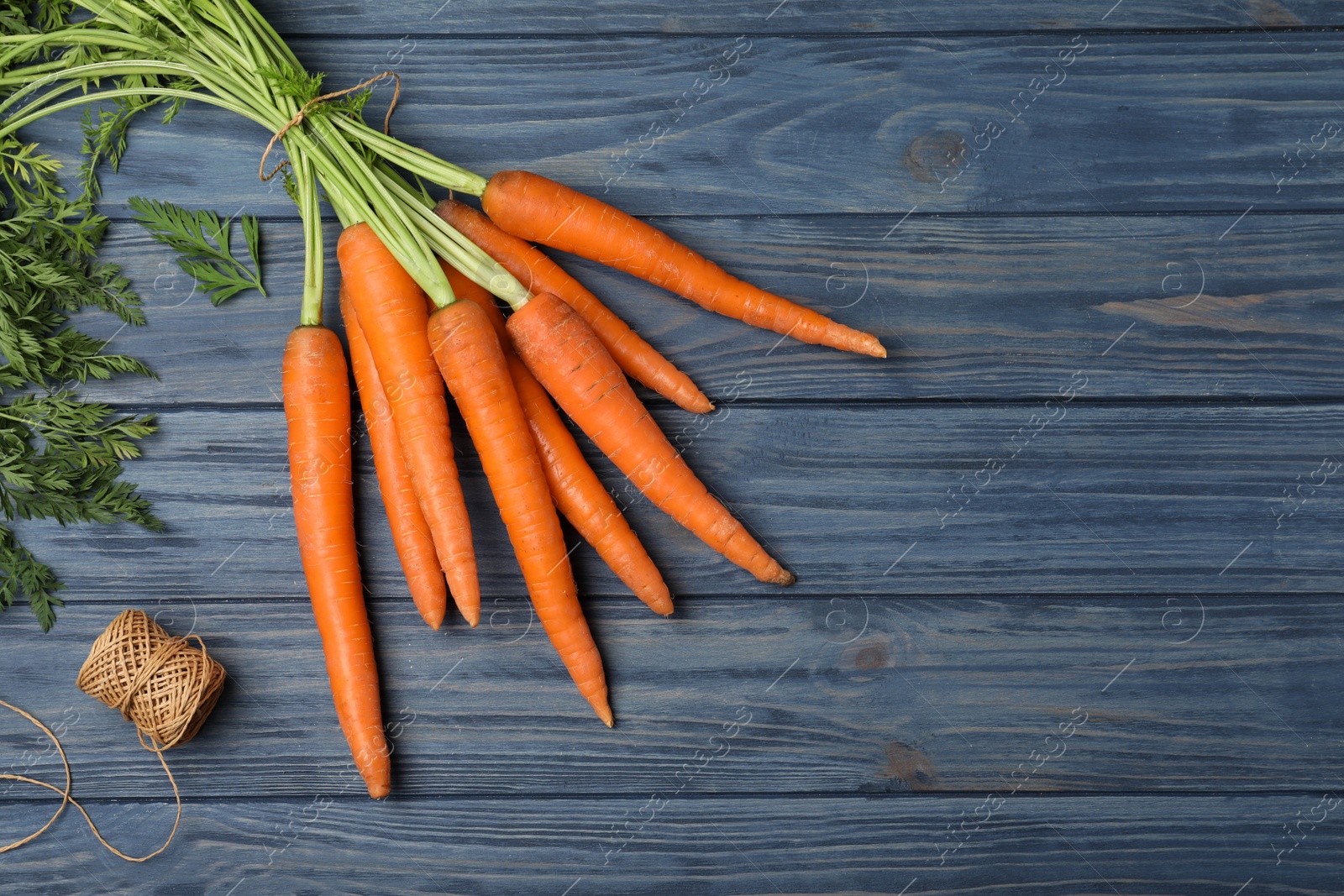 Photo of Flat lay composition with carrots on wooden background. Space for text