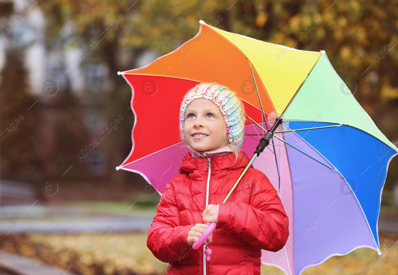 Photo of Little girl with umbrella in autumn park on rainy day