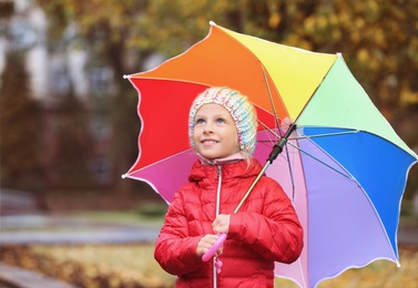 Photo of Little girl with umbrella in autumn park on rainy day