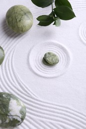 Photo of Zen concept. Stones, leaves and pattern on white sand, above view