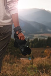 Photo of Professional photographer with modern camera in mountains, closeup