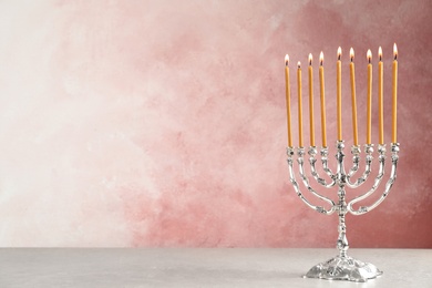 Photo of Hanukkah menorah on table against color background