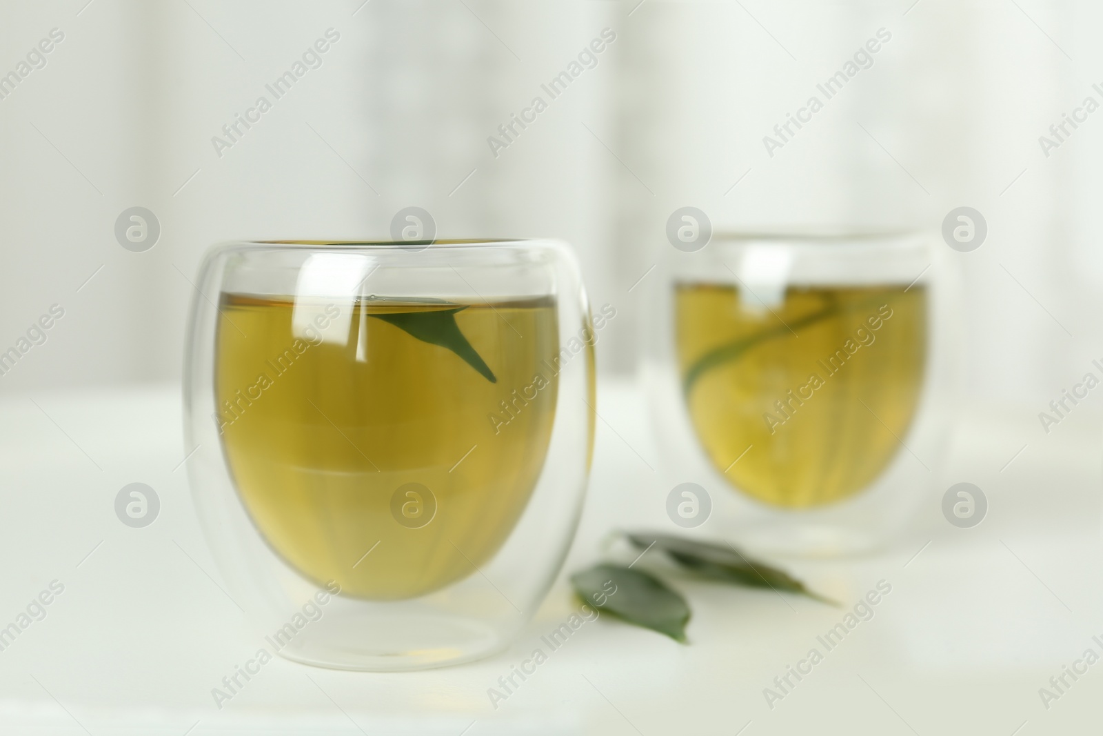 Photo of Aromatic green tea and leaves on white table