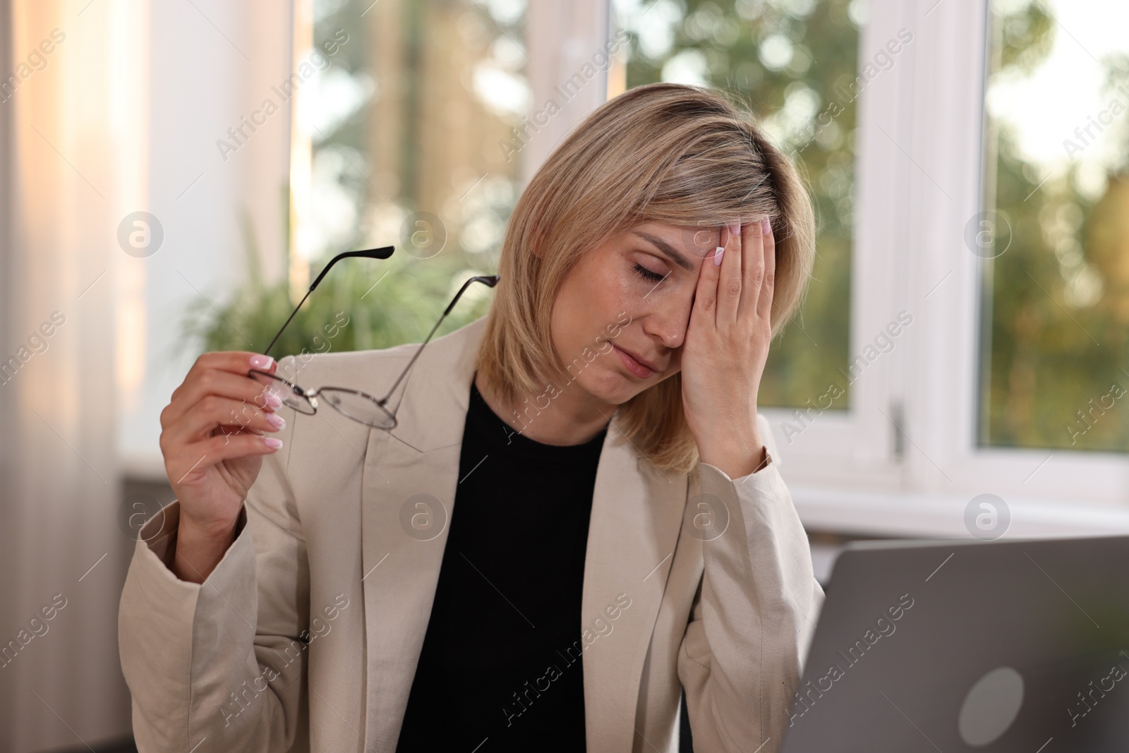 Photo of Overwhelmed woman sitting at table in office