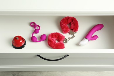 Photo of Different modern sex toys in open wooden drawer, above view