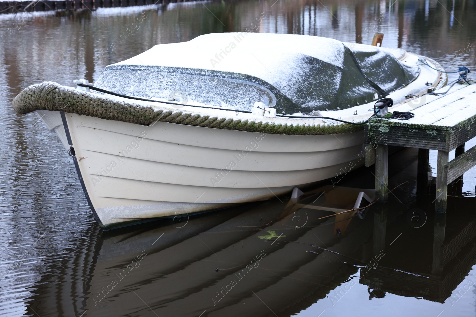 Photo of Water canal with moored boat on winter day