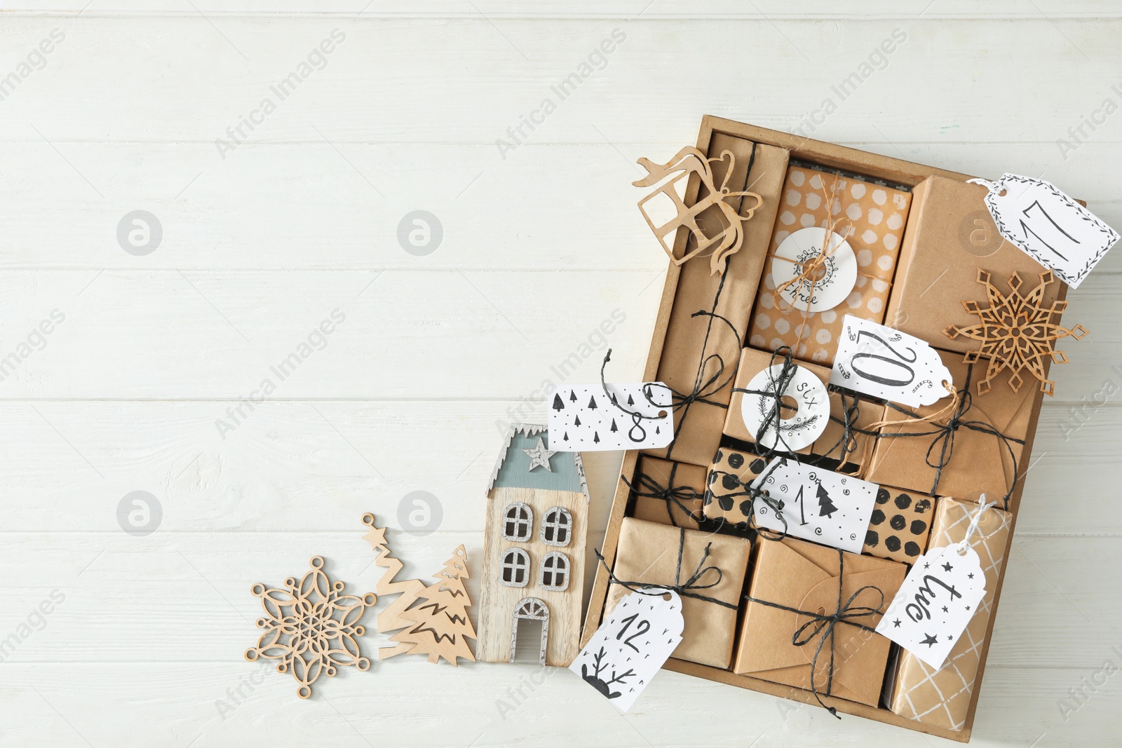 Photo of Gift boxes and festive decor on white wooden table, flat lay with space for text. Christmas advent calendar