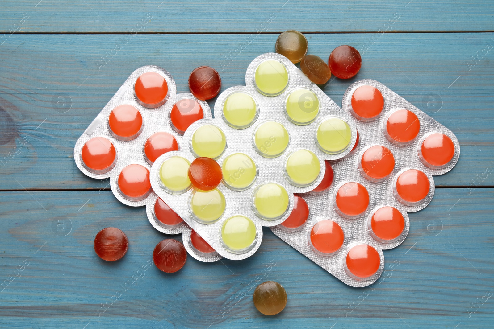 Photo of Colorful cough drops on blue wooden background, flat lay