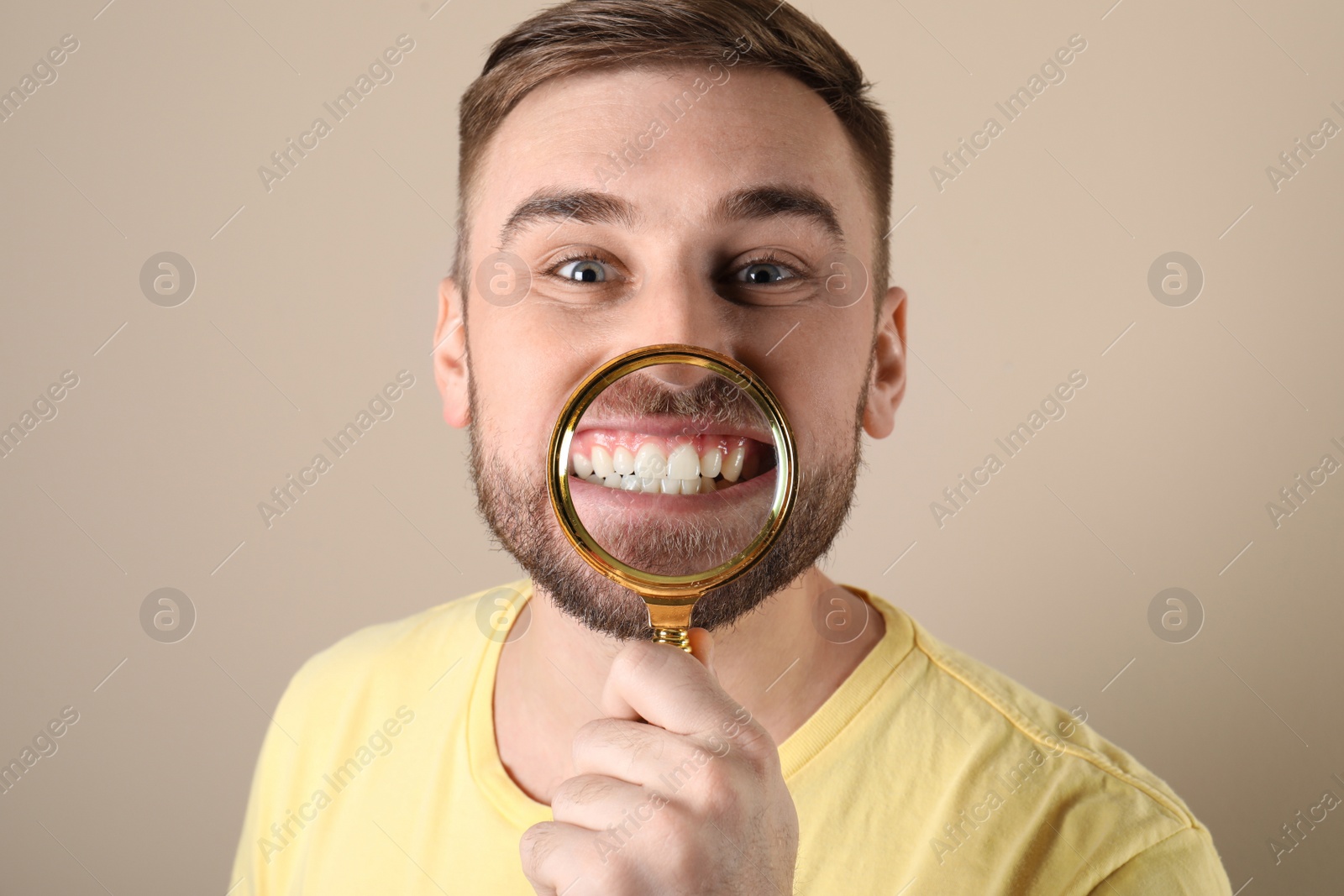 Photo of Young man with healthy teeth and magnifier on color background