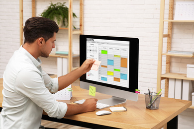 Photo of Handsome man using calendar app on computer in office